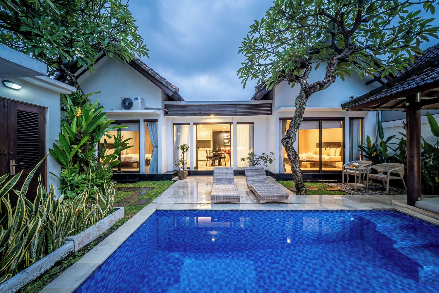 A modern house with a swimming pool, outdoor seating, and a well-maintained garden.