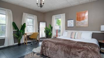 Een slaapkamer met een groot bed, een bureau en twee potplanten.