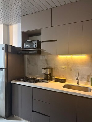 A modern kitchen with a built-in oven, a coffee maker, and a sink.