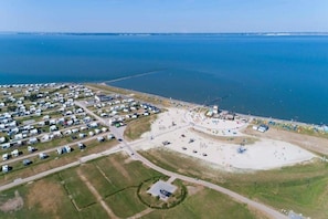 An aerial view of a coastal area with RVs, a beach, and a pier.