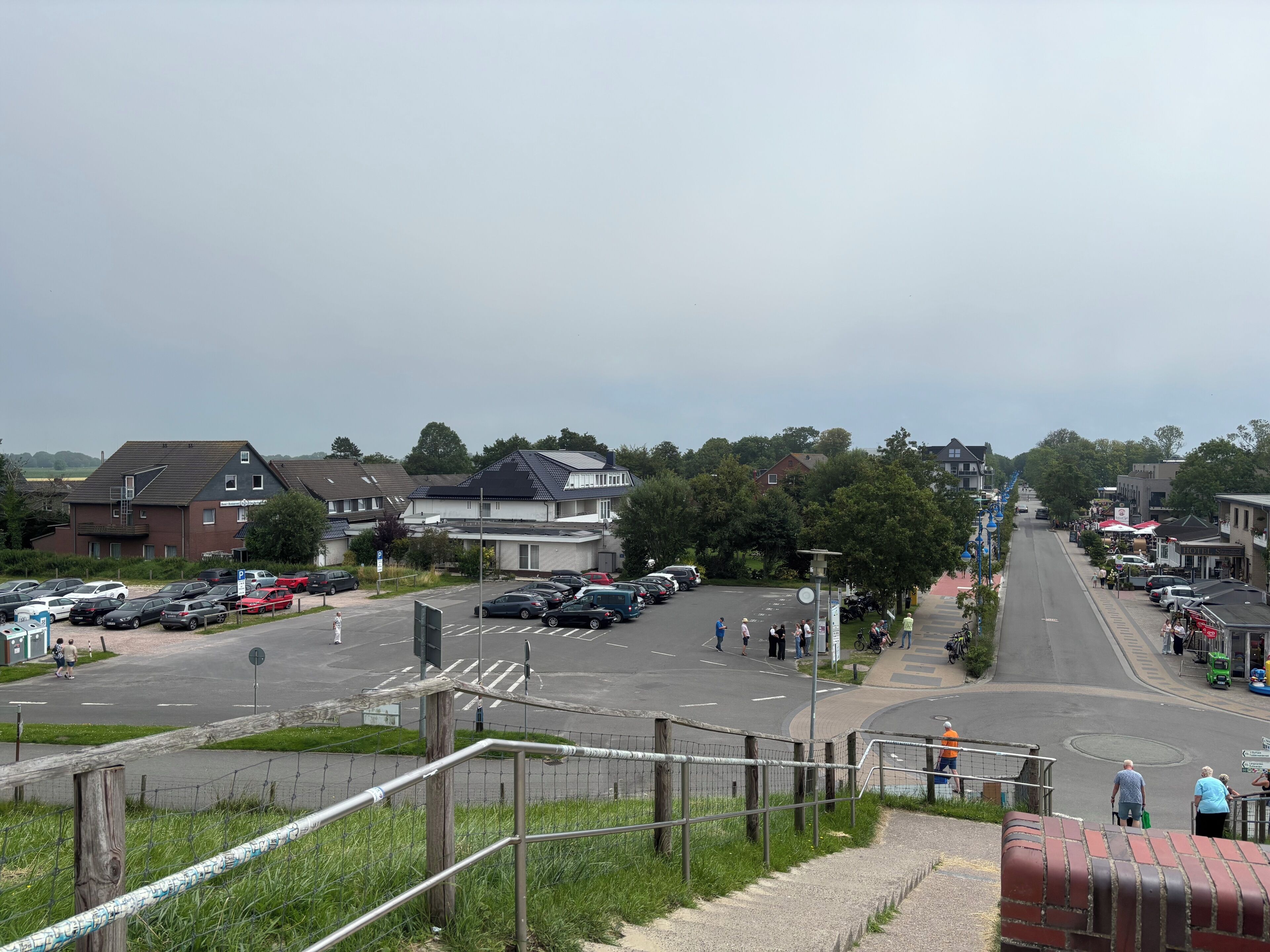 Straßenansicht mit parkenden Autos, einer Fußgängerampel und Gebäuden mit Geschäften.