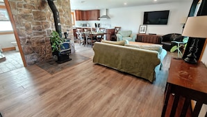 Un salon avec un mur en pierre, un canapé, un téléviseur et une cheminée.