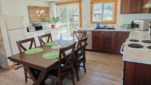 Une cuisine moderne avec des meubles en bois, une table à manger avec des chaises et une vue sur l’extérieur.