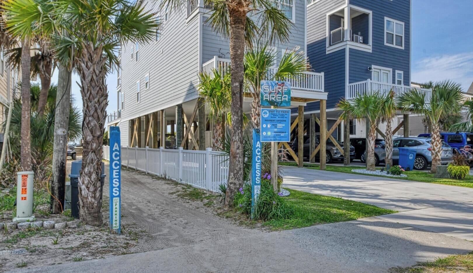 A beachfront property with a 'Surf Area' sign, a 'Pay to Park' sign, and a 'Parking Only' sign.