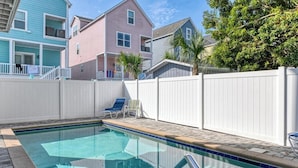 A swimming pool with a white fence, two lounge chairs, and a multi-story building in the background. - Seven C's - Five Bedroom Five & a Half Bath Third Row Home with Private Pool (Surfside Beach)