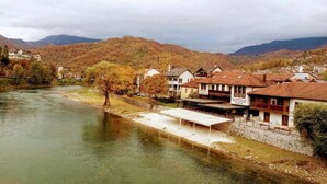 A riverside view with buildings, a bridge, and mountains in the background.