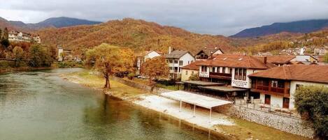 A riverside view with buildings, a bridge, and mountains in the background.