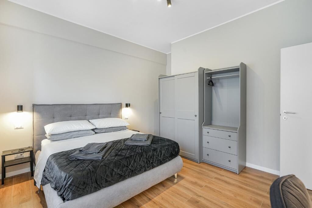 Une chambre à coucher comprenant un lit, des tables de chevet, une armoire et un placard.