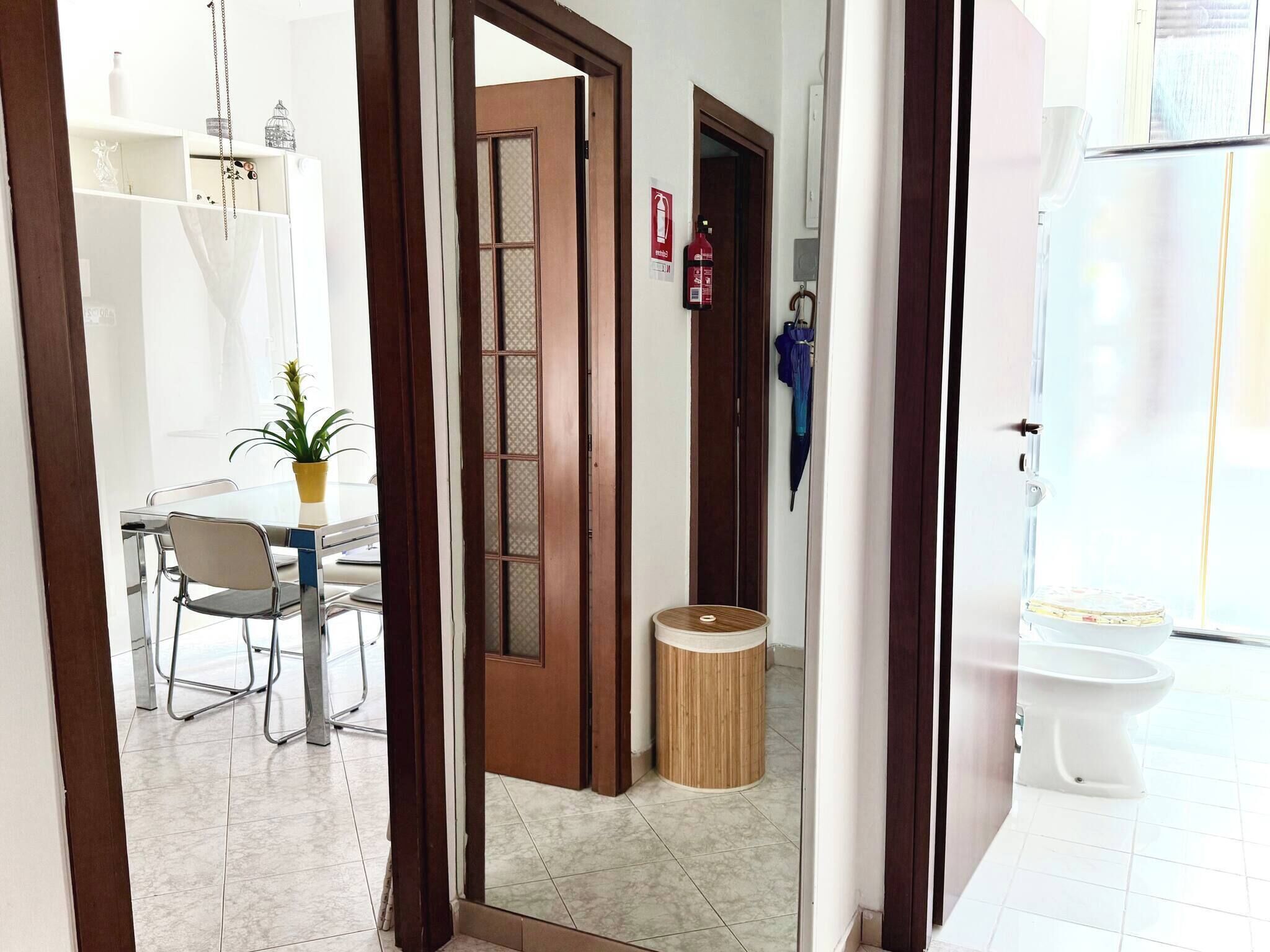 A hotel room with a dining area, a wooden door, a small round table, and a toilet.