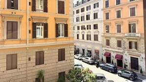 A multi-story hotel with a classic architectural style, featuring a central courtyard with parked cars and a few potted plants. - Central Rome Apartment Termini - Roman Haven (Rome)