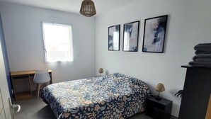 A bedroom with a bed, a desk, a chair, a lamp, and two abstract paintings on the wall. - Spacious single-story house (Villeneuve-en-Retz)