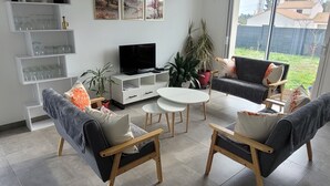 A modern living room with a flat-screen TV, two sofas, a coffee table, and a dining table. - Spacious single-story house (Villeneuve-en-Retz)