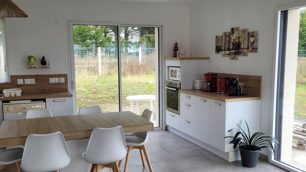 A modern kitchen with a dining table, chairs, and a hanging light fixture. - Spacious single-story house (Villeneuve-en-Retz)