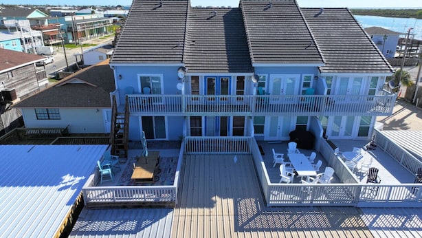Ein zweistöckiges Haus mit einer Terrasse, einer kleinen Veranda und Blick auf den Ozean.