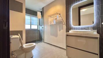 A modern bathroom with a toilet, shower, and sink.