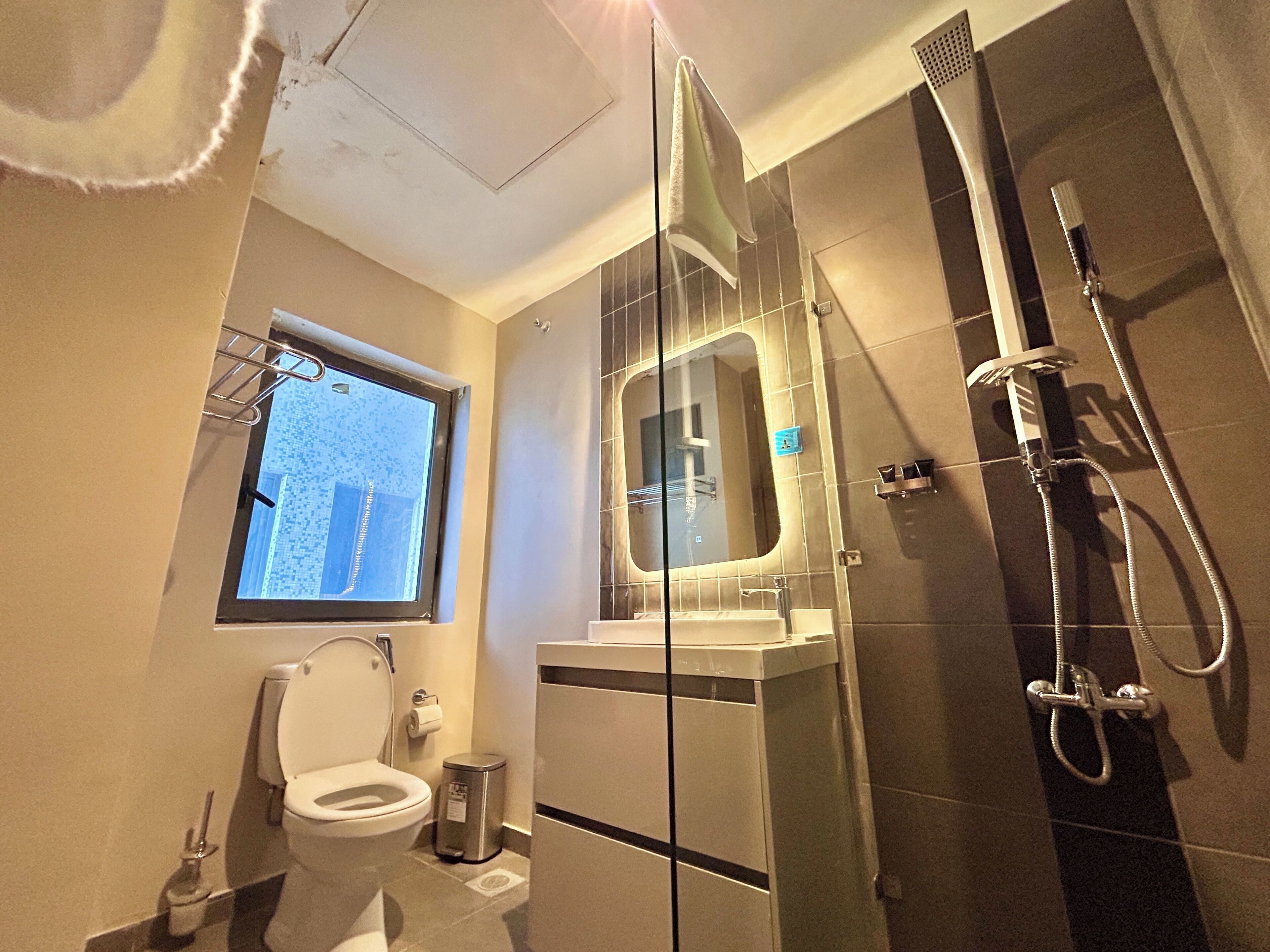 A modern bathroom with a toilet, a sink, a mirror, and a shower.