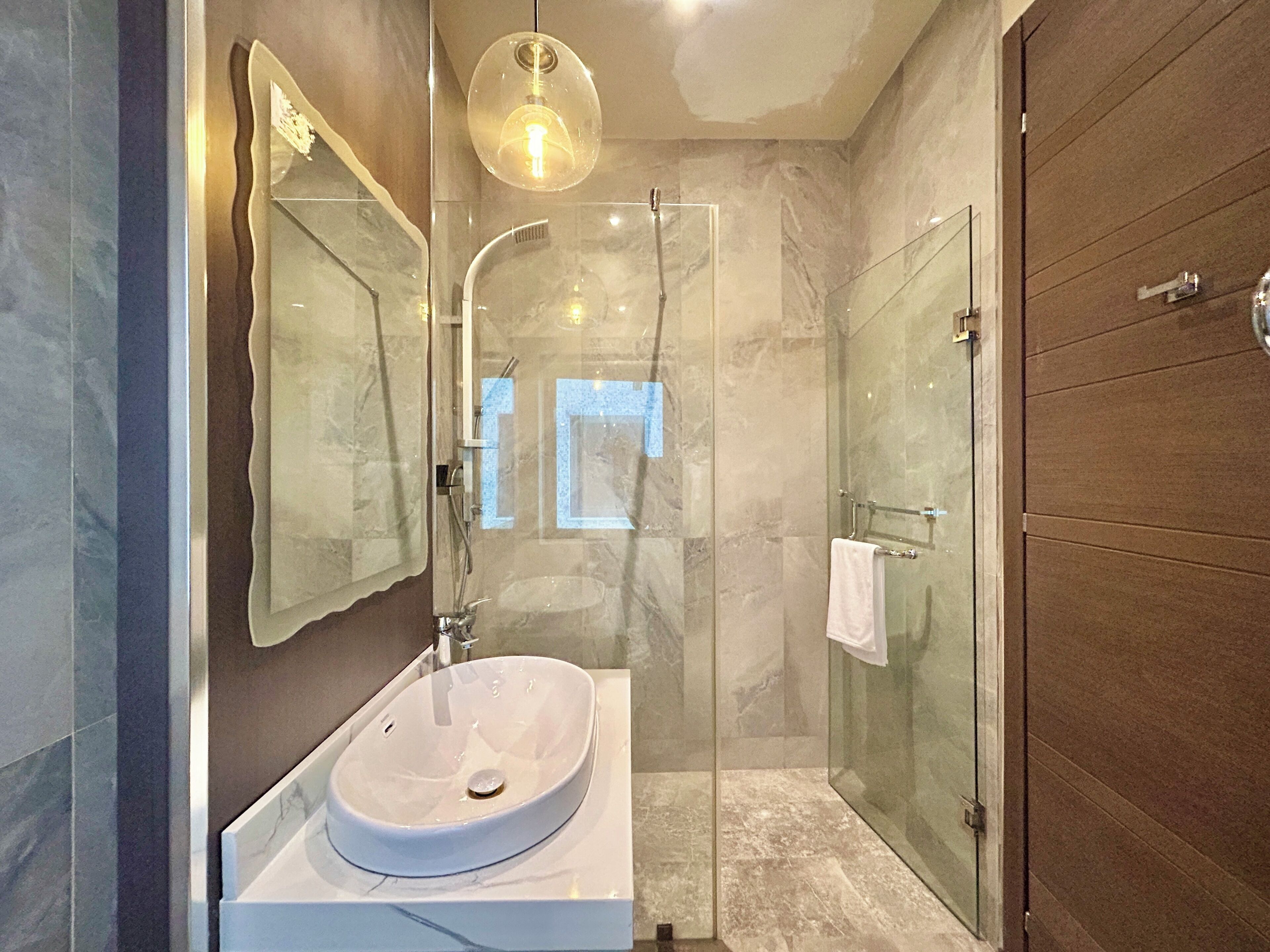 A modern bathroom with a glass shower enclosure, a white sink, and a large mirror.