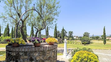 Ein Garten mit Steinarchitektur, Pflanzgefäßen und blauem Himmel.
