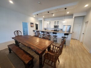 Een ruime keuken met een centraal kookeiland, een houten eettafel en barstoelen.