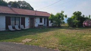 Ein Haus mit rotem Ziegeldach, einer Veranda mit Stühlen und einem gepflegten Rasen.