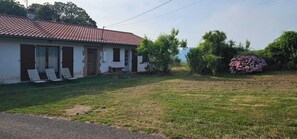 Ein Haus mit rotem Ziegeldach, einer Veranda mit Stühlen und einem gepflegten Rasen.