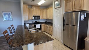 A kitchen with granite countertops, stainless steel appliances, wooden cabinets, and a dining area with chairs. - Waterview Home with Two Private Boat Lifts (Port O`Connor)