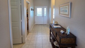 A hallway with a tiled floor, a wooden bench, a door, and a ceiling light fixture. - Waterview Home with Two Private Boat Lifts (Port O`Connor)