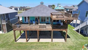 A two-story house with a deck, a covered patio, and a small outdoor seating area. - Waterview Home with Two Private Boat Lifts (Port O`Connor)