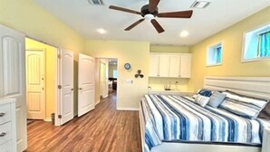Ein Schlafzimmer mit einem Bett, einem Deckenventilator, Holzboden und weißen Schränken.