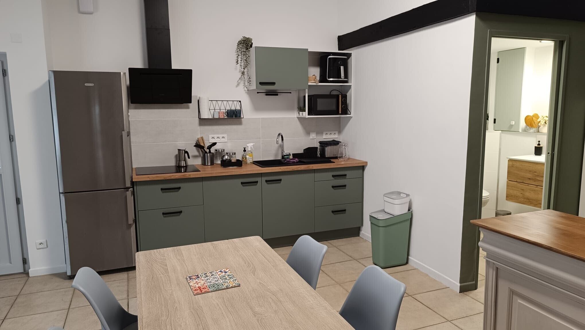 A compact kitchen with a refrigerator, microwave, sink, and a dining table with chairs.