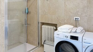 Ein modernes Badezimmer mit Duschkabine aus Glas, integriertem Heizkörper und einer Frontlademaschine.