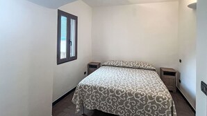 Ein Schlafzimmer mit einem Bett, einem Fenster und einem Nachttisch.