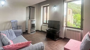 Ein Wohnzimmer mit Sofa, Fernseher, Kamin und einem Fenster mit Aussicht.