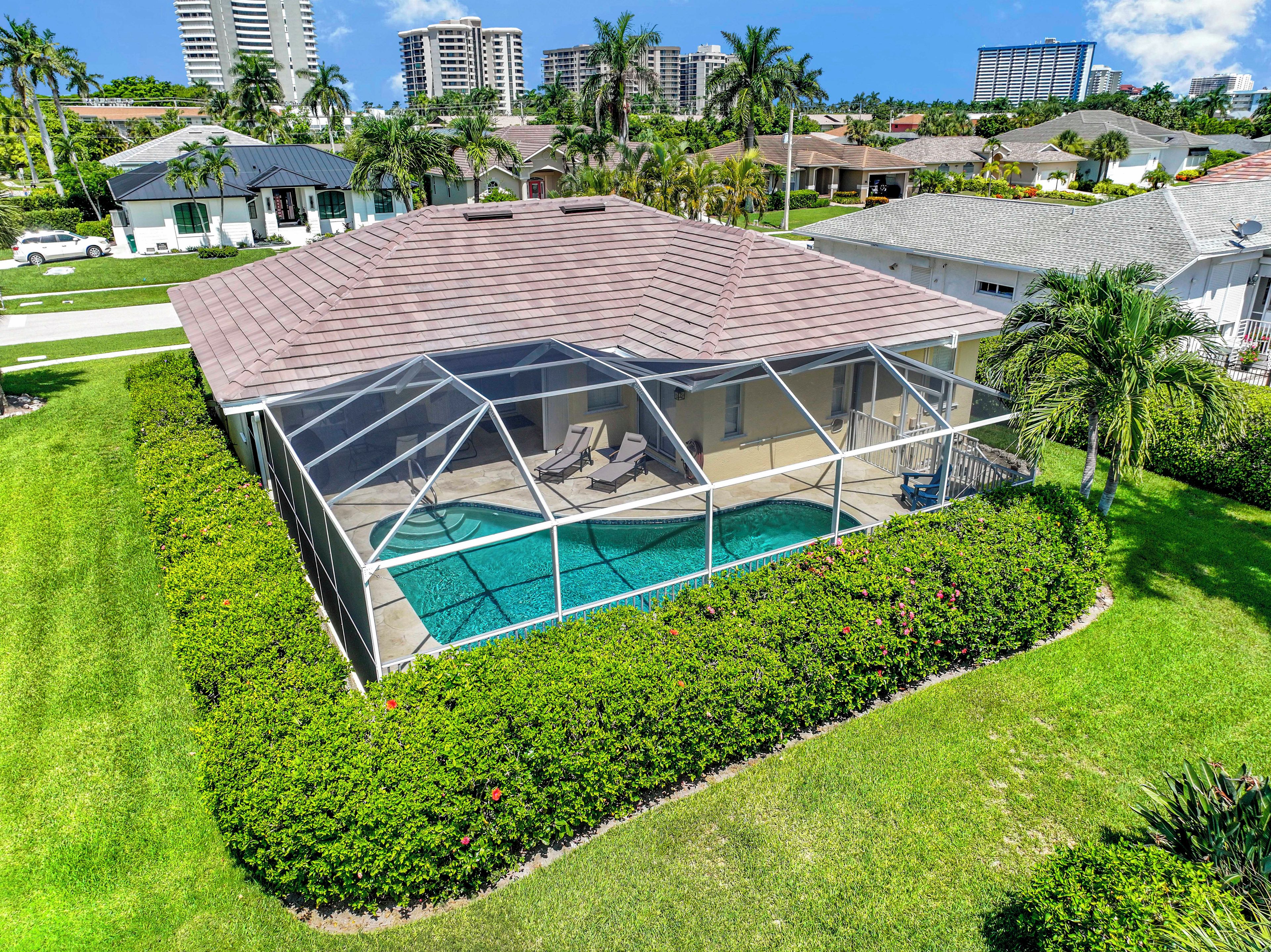 A residential property with a swimming pool, covered patio, and lush landscaping.