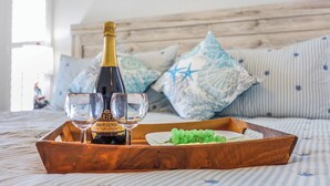 Una cama con cabecera de madera, una botella de champán Brut Cuvée, dos copas y una bandeja con uvas.
