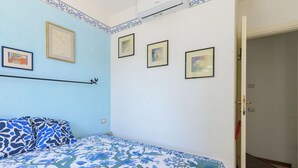 Un dormitori amb un llit, una estantanya penjada a la paret i una porta que dona a una altra habitació.