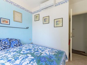 Ein Schlafzimmer mit einem Bett, einer Wandablage und einer Tür zu einem anderen Raum.