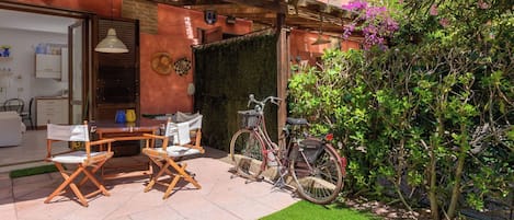 A patio with a table and chairs, a bicycle, and a small garden area.