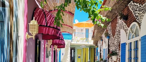 Un callejón estrecho con edificios coloridos, una zona de recepción y cielo despejado.