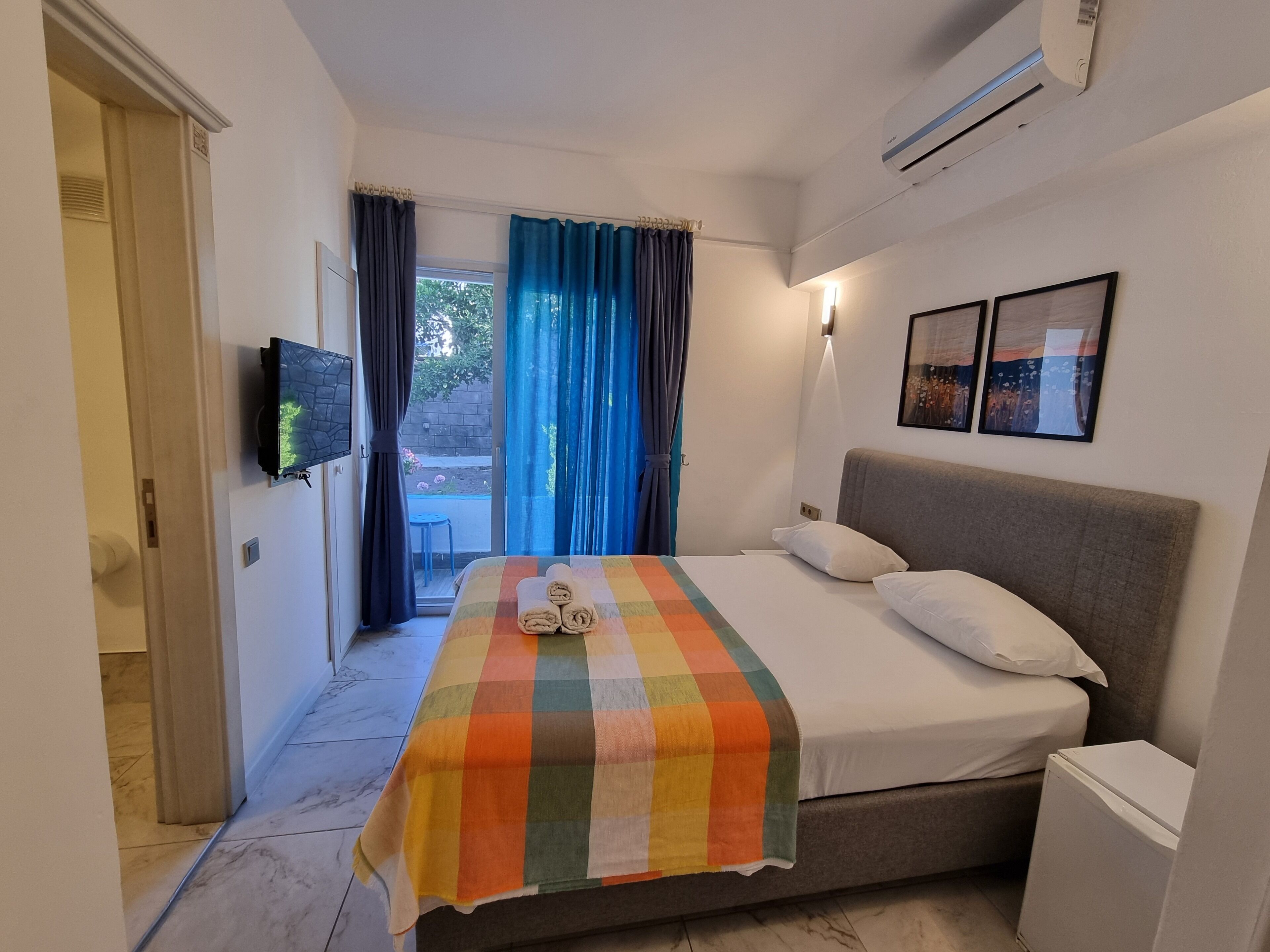 Habitación de hotel con cama, televisión, una mesita y vistas al exterior.