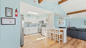 Une cuisine moderne avec des meubles blancs, un îlot central et un coin repas avec des chaises blanches.