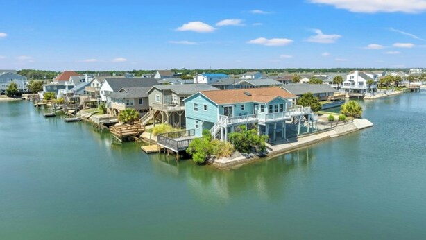 Une propriété située au bord de l’eau, dotée d’un quai, d’une maison à la façade bleue et d’un petit bateau.