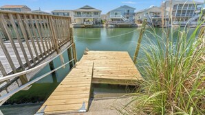 Une jetée en bois menant à une marina, avec des maisons en arrière-plan.