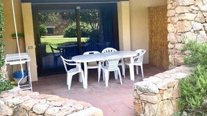 An outdoor patio with a table and chairs, a stone wall, and a view of a garden. - P.Rotondo1 B106 S, two-room apartment with 5 beds (Porto Rotondo)