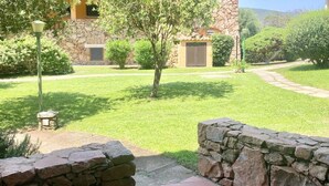 A stone building with a stone wall, a paved path, and a well-maintained lawn. - P.Rotondo1 B106 S, two-room apartment with 5 beds (Porto Rotondo)