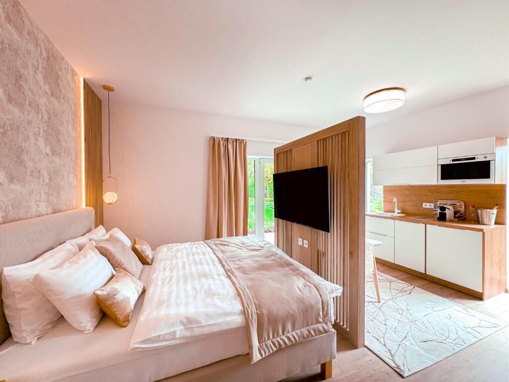 Una habitació d'hotel moderna amb un llit, una televisió, una zona de cuina i vista a l'exterior.