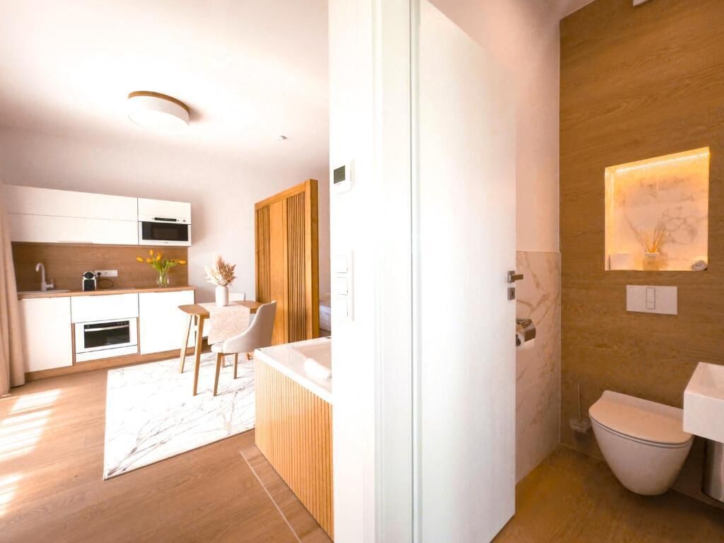 Una cocina moderna con armarios blancos, encimera de madera y un comedor con una silla y mesa blancos.