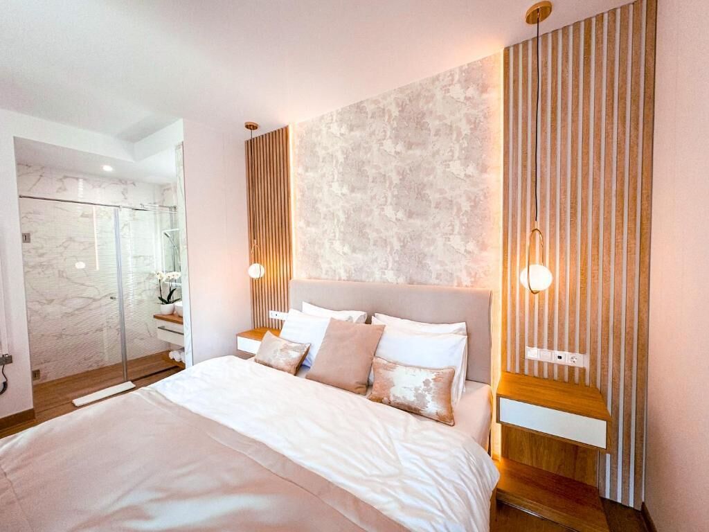 Una camera da letto moderna con un letto grande, una cabina doccia in vetro e un parete con texture.