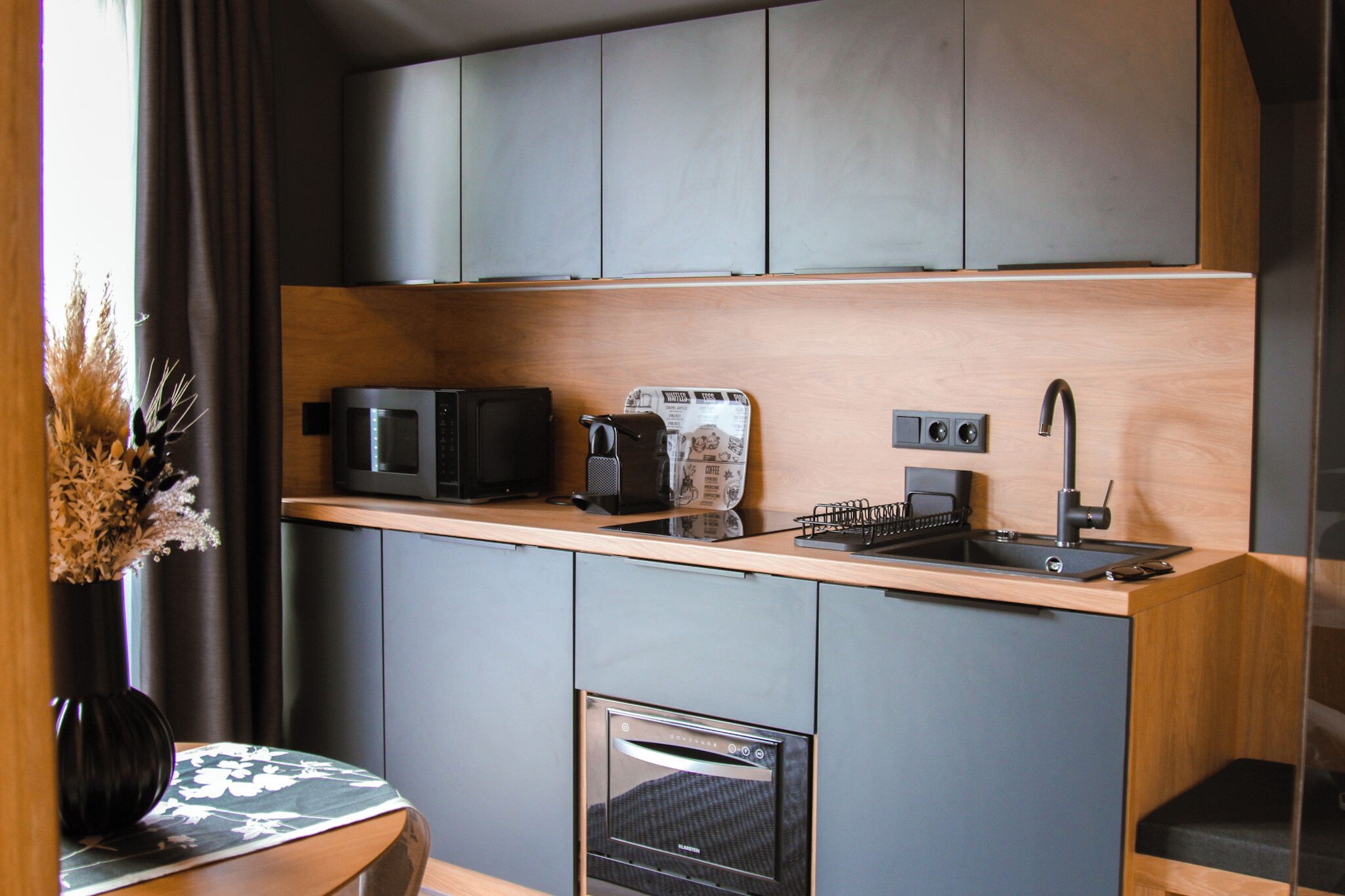 Una cocina compacta con microondas, tostadora, cafetera y horno empotrado.