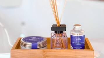 Een houten dienblad met een verdamper, een fles etherische olie en een potje rietstokjes op een badkamermeubel.